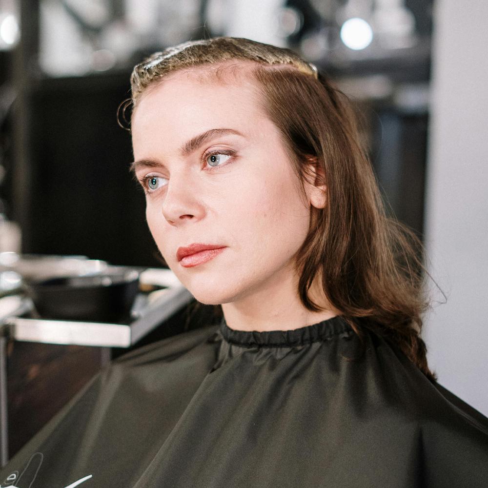 Žena v kadern&iacute;ckom sal&oacute;ne s jemn&yacute;m rednut&iacute;m vlasov pri čele